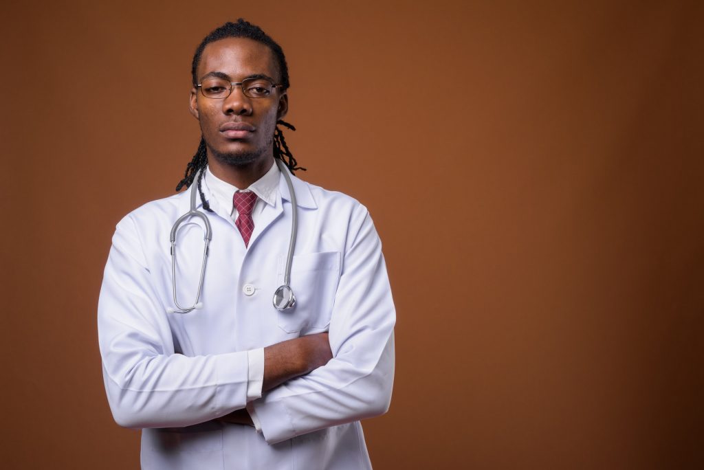 Young handsome African man doctor against brown background